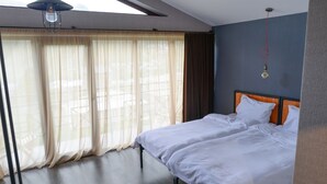 Una camera d'albergo con un letto grande, un lampadario a soffitto e vista attraverso tende leggere.
