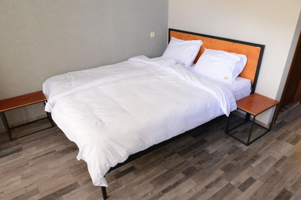 A single bed with white bedding, a wooden headboard, and a small bedside table with a lamp.