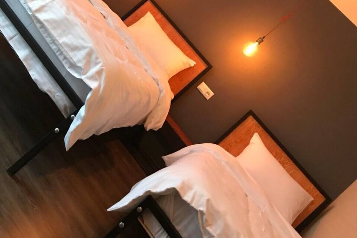 A hotel room with two beds, each with white linens, and two wall-mounted light fixtures.