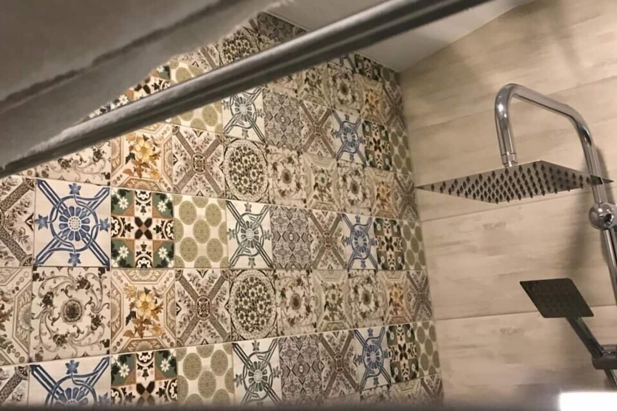 A bathroom with a tiled wall featuring a variety of geometric and floral patterns.