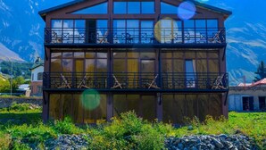 Un edificio a due piani con un balcone, con l'insegna "Chemadonn Hotel", circondato da montagne.