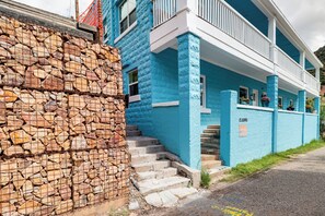 Edifici de dues plantes amb una paret de pedra a l'esquerra i façana blava amb adorns blancs.