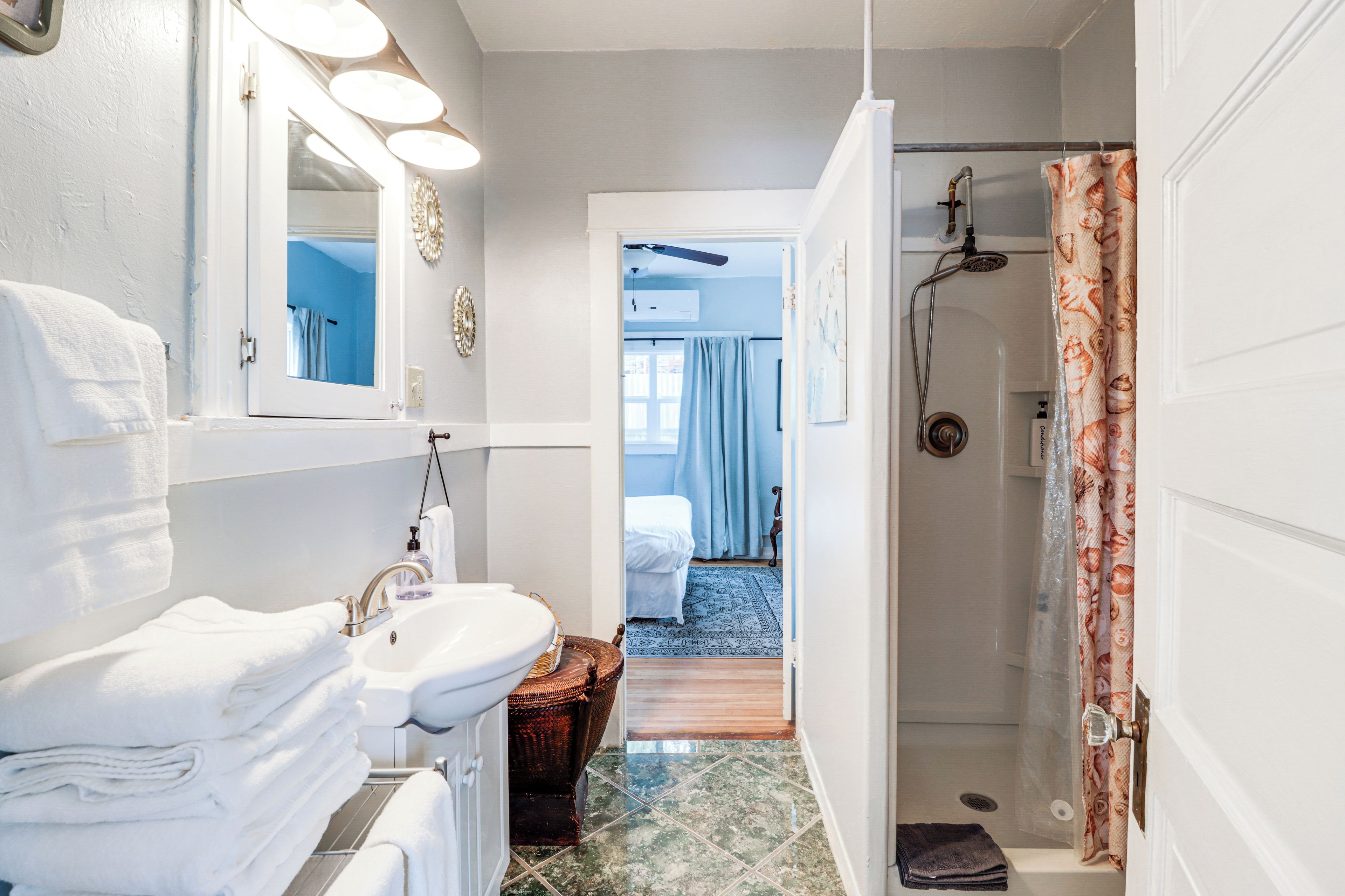 A bathroom with a sink, mirror, and shower.