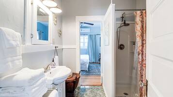 A bathroom with a sink, mirror, and shower.