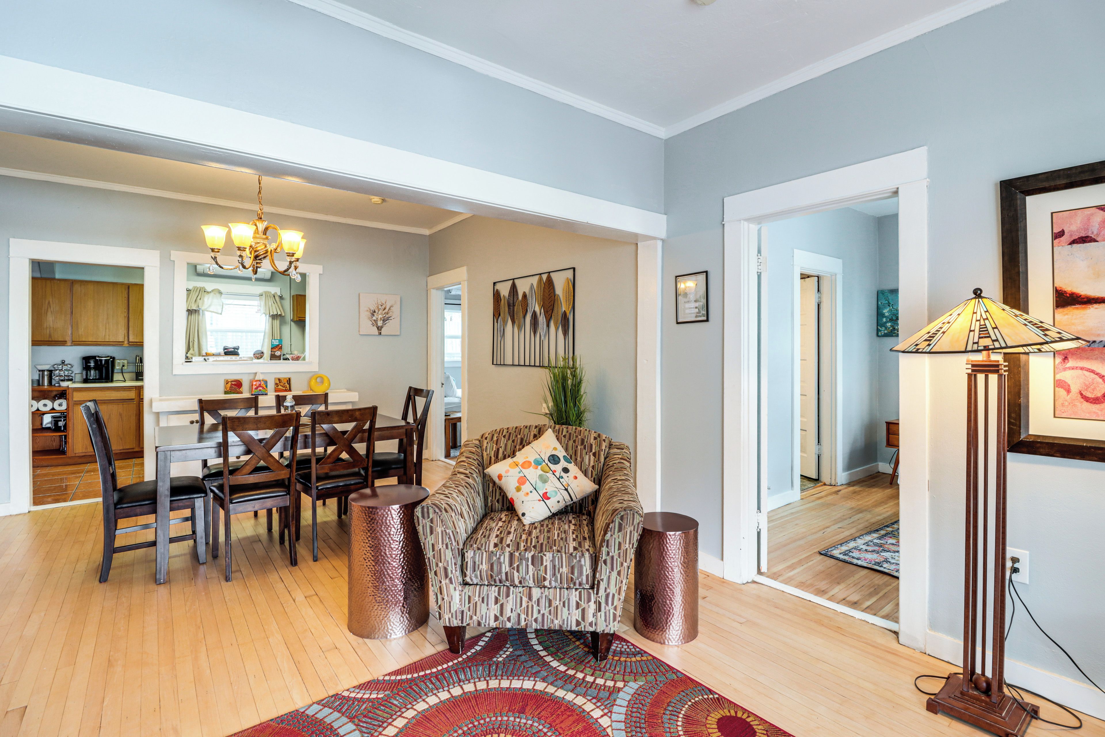 A spacious living room with a dining area, a kitchen, and a hallway leading to another room.