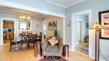A spacious living room with a dining area, a kitchen, and a hallway leading to another room.