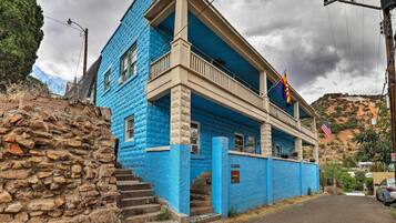 A two-story building with a blue exterior, a balcony, and a flag.
