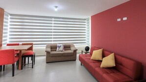 A modern living room with a red couch, beige sofa, and a dining table with red chairs. - Apartments Cumbaya Quito Ec (Cumbayá)