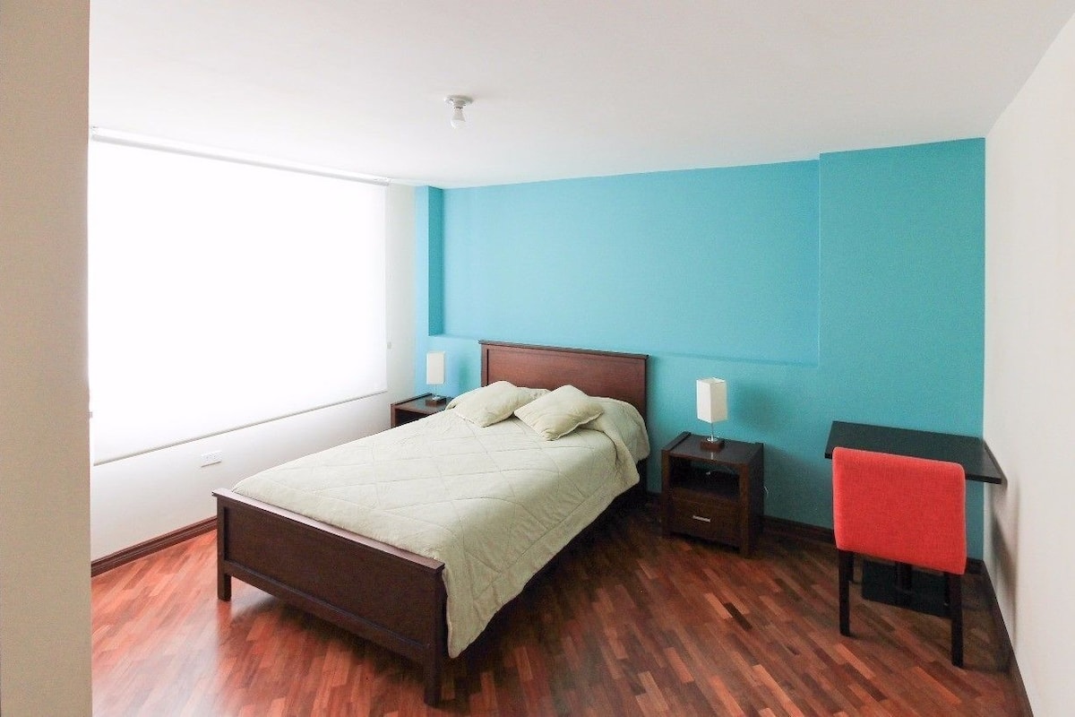 Une chambre à coucher avec un lit, des tables de chevet, un bureau et une chaise.