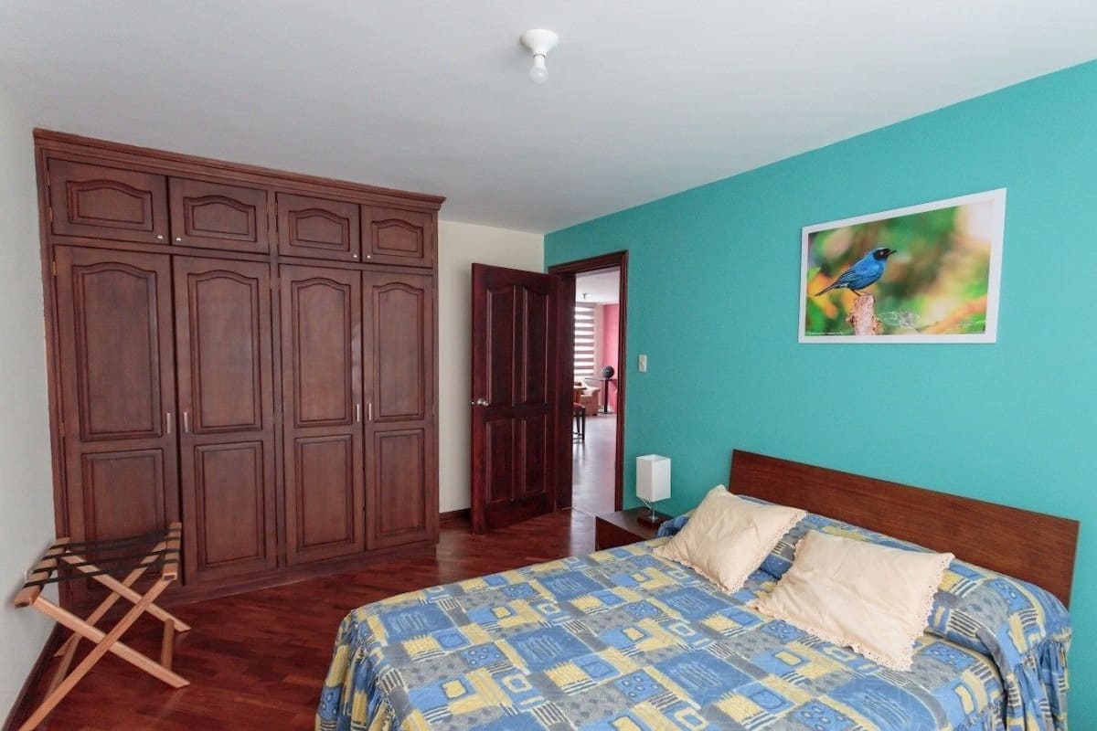 Une chambre à coucher avec un lit, une armoire en bois et un tableau représentant un oiseau accroché au mur.