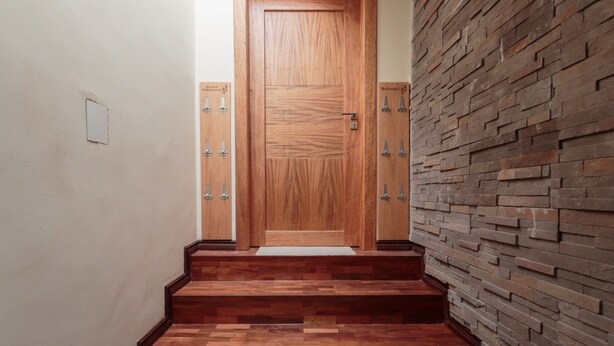 A wooden door with a textured surface, flanked by two wall-mounted sconces. - Apartments Cumbaya Quito Ec (Cumbayá)