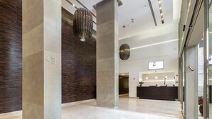 A modern lobby with a reception desk, a large pillar, and a hanging light fixture.