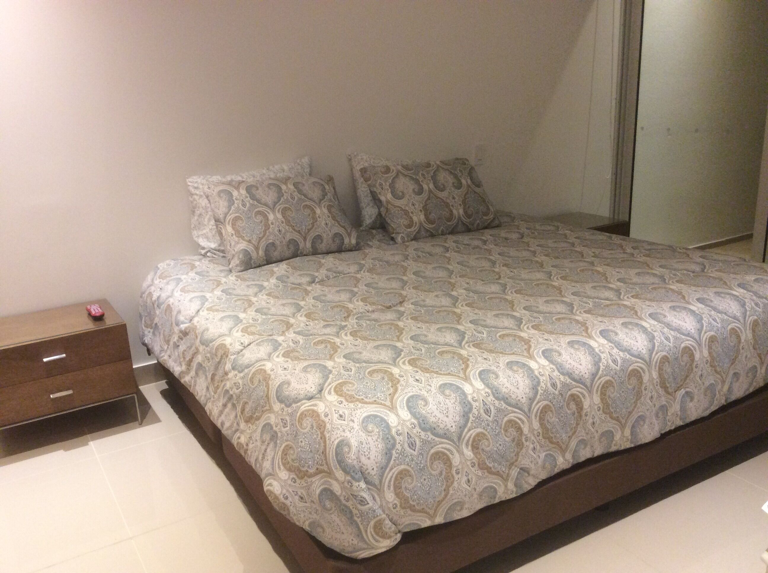 Una camera da letto con un letto, due cuscini, un comodino e un cassetto.