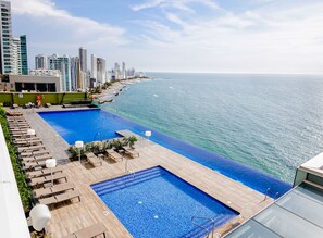 Una piscina en la azotea con vistas al océano y edificios altos.