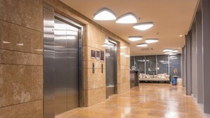 A modern elevator area with a marble floor and a seating area with a sofa and cushions. - 1703 Apartamento Luxury en Edificio H2 Condominio (Cartagena)