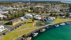 An aerial view of a coastal residential area with a marina, houses, and a large building with a swimming pool. - Two Storey Apartment Sandcastle 7 (Tuncurry)