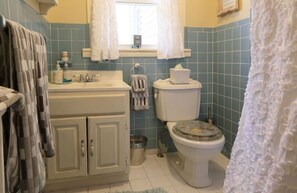 Ein Badezimmer mit Waschbecken, Toilette und einem Fenster mit Vorhängen.