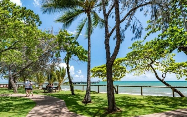 Stroll along the paved walkway and enjoy the serene ocean views surrounded by lush trees and a picturesque pier.