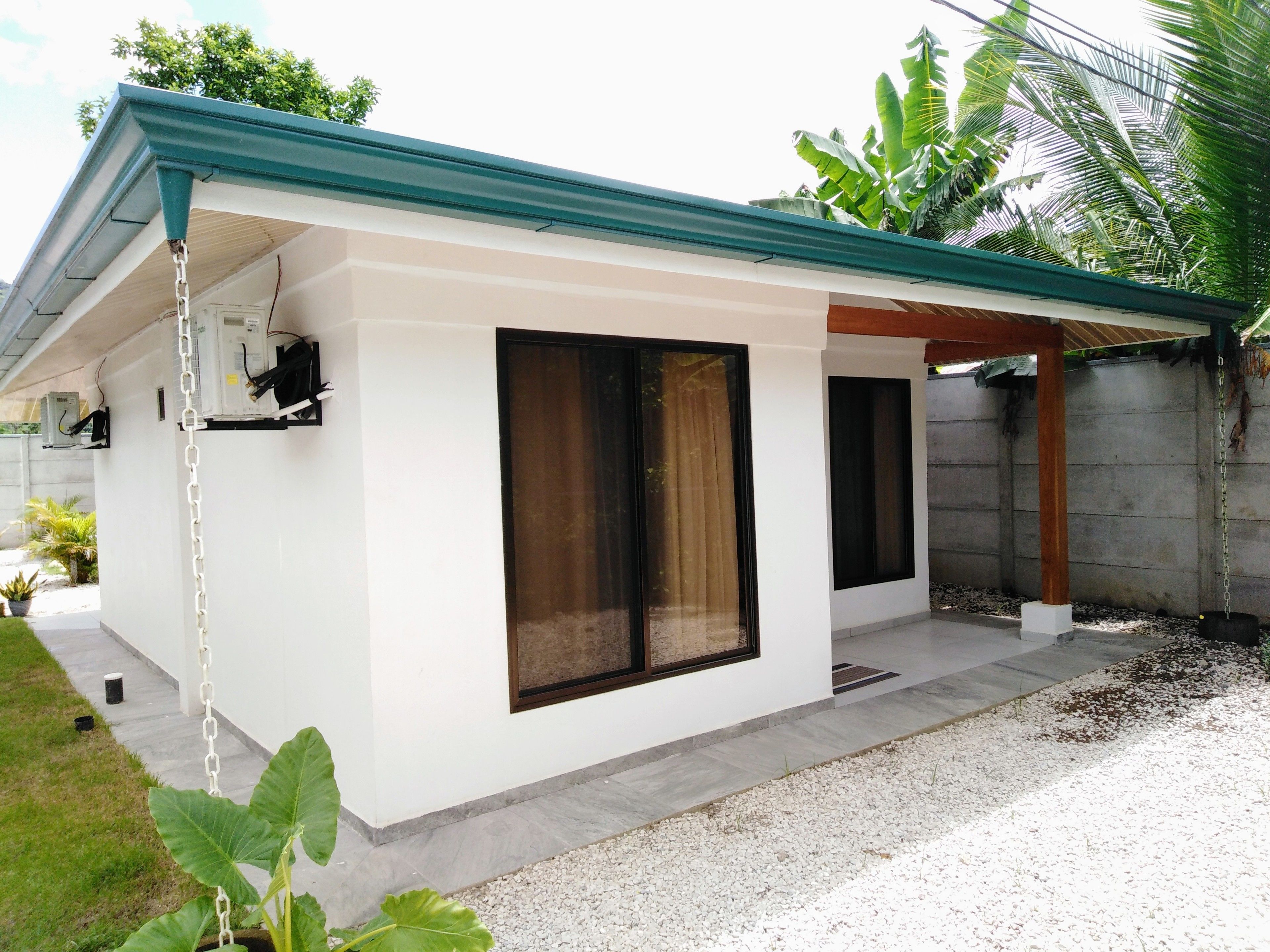 A modern house with a covered patio, large windows, and a concrete wall.
