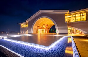 A modern building with a large arched entrance and a tiled pool area. - Seawood Hotel (Miyakojima)