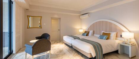 A hotel room with a large bed, a desk with a chair, a mirror, and a window.