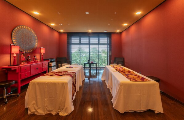 A room with two beds, a red desk, and a large window with blinds. - Seawood Hotel (Miyakojima)
