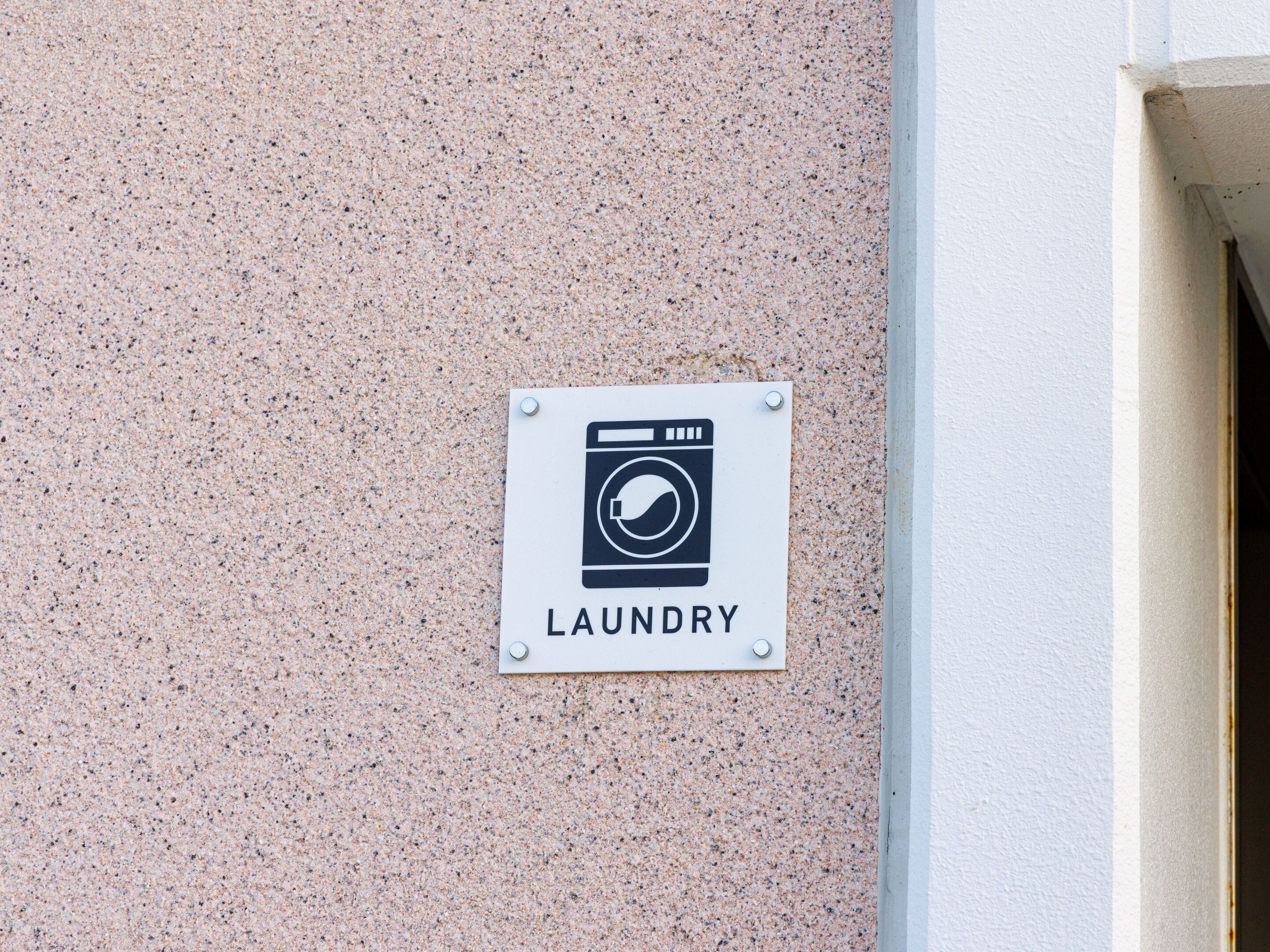 A sign indicating a laundry facility on a textured wall.