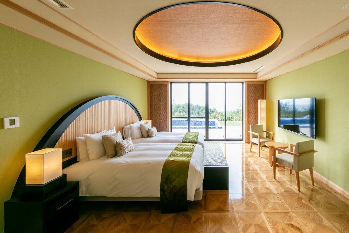Ein Hotelzimmer mit Bett, Fernseher, Schreibtisch und Blick auf einen Swimmingpool.