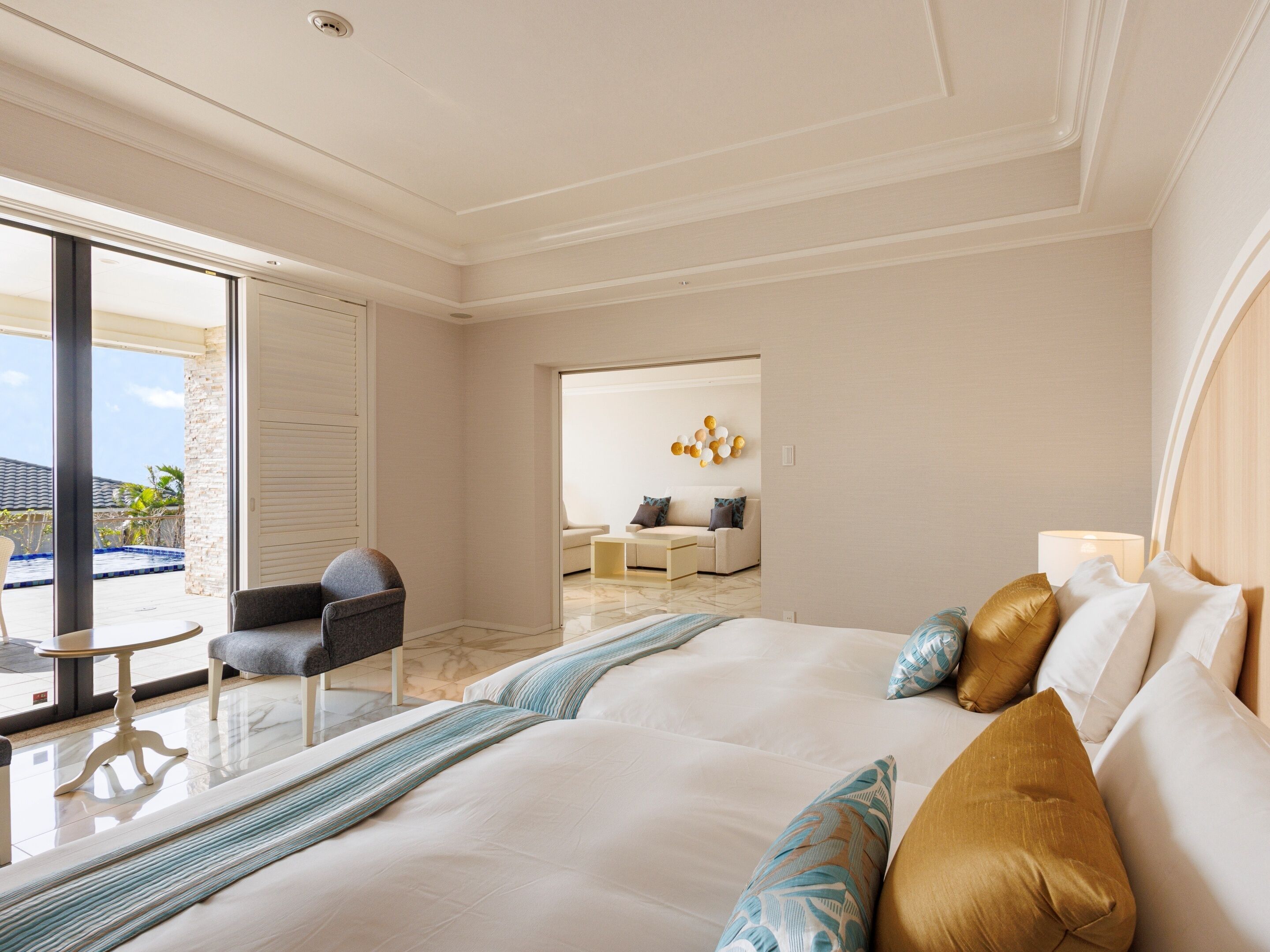 Una habitación de hotel moderna con una cama grande, un área de descanso con una mesa y sillas, y vista a la piscina.