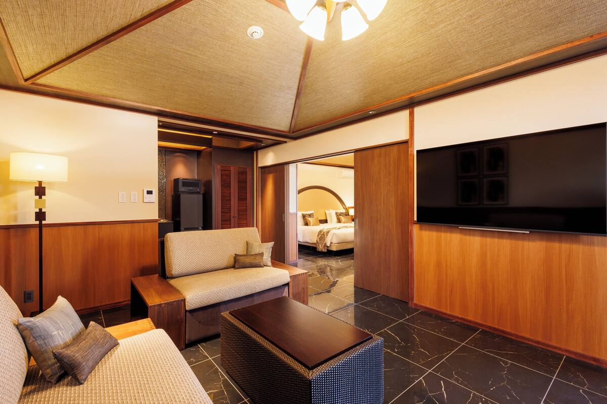 Ein Hotelzimmer mit einer Couch, einem Couchtisch, einem Fernseher und einem Holzkasten.