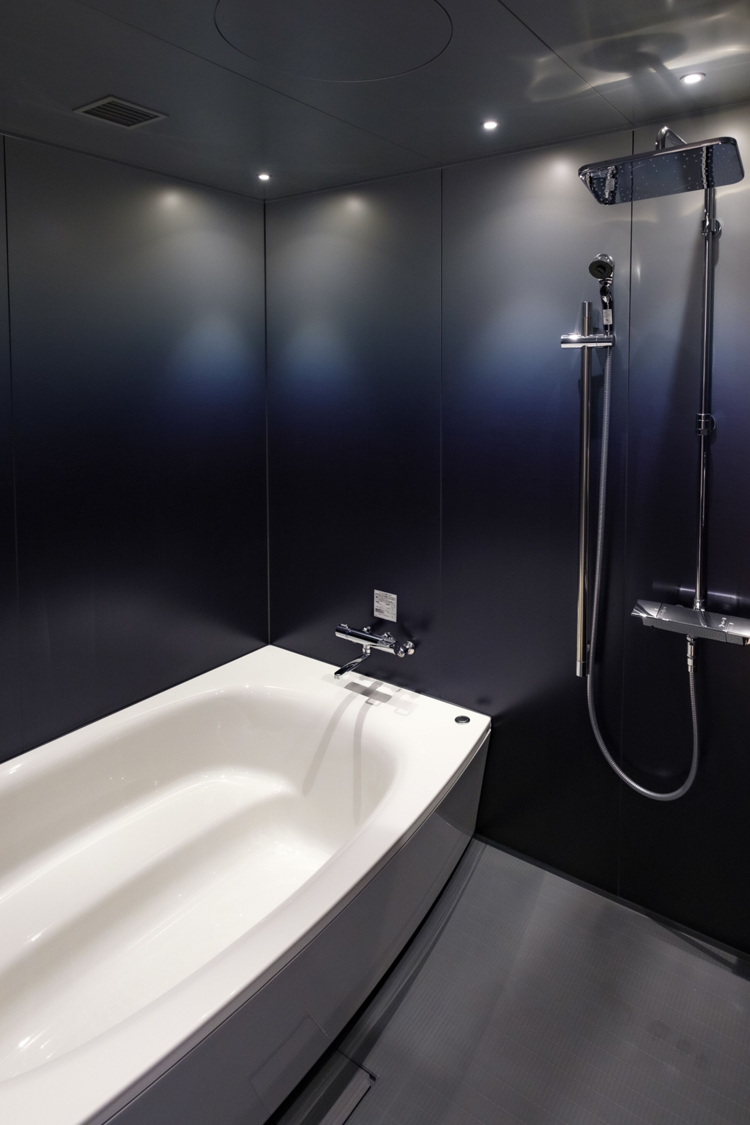 A modern bathroom with a large white bathtub, a showerhead, and a wall-mounted faucet.