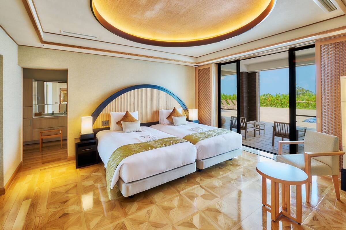 Ein Hotelzimmer mit einem großen Bett, einem Schreibtisch, einem Sessel und einem Balkon mit Blick.