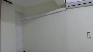 Una stanza con una sedia, un condizionatore d'aria bianco e una presa elettrica a parete.