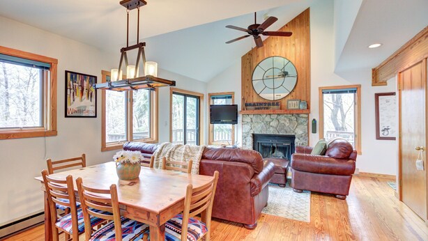 A spacious living area with a fireplace, leather sofas, a dining table with chairs, and a ceiling fan. - Relaxing 3 bdrm Mountain Cabin on Wintergreen Resort (Wintergreen Resort)
