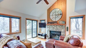 A spacious living room with leather sofas, a stone fireplace, and large windows. - Relaxing 3 bdrm Mountain Cabin on Wintergreen Resort (Wintergreen Resort)