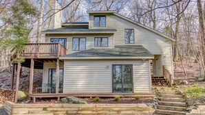 A two-story house with a wooden deck, a covered porch, and a stone retaining wall. - Relaxing 3 bdrm Mountain Cabin on Wintergreen Resort (Wintergreen Resort)