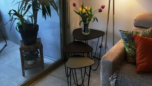 Een gezellige zithoek met een bank, een klein rond tafeltje, een vloerlamp en een potplant.