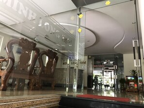 Ein Hotel Eingang mit Glasfassade, einem Holzstuhl davor und einem Schild mit der Aufschrift "Min Long Hotel".