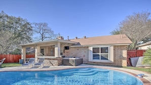 Een achtertuin met een zwembad, een jacuzzi en een overdekte patio.