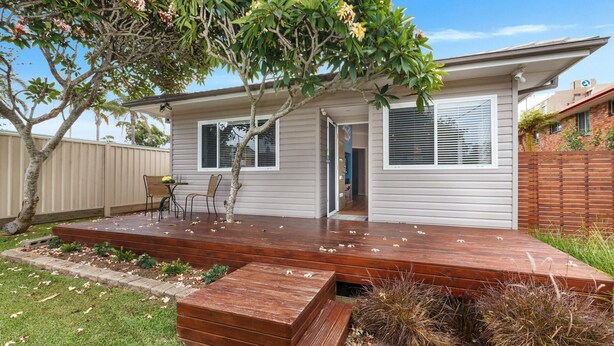 A single-story house with a wooden deck, a small porch, and a covered outdoor seating area. - Sandy Toes - park the car and walk everywhere! (Forster)