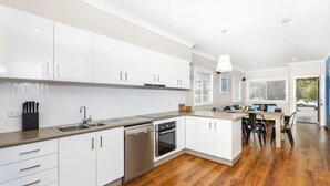 A modern kitchen with white cabinets, stainless steel appliances, and a wooden floor. - Sandy Toes - park the car and walk everywhere! (Forster)
