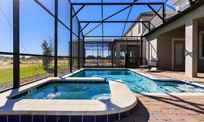 A swimming pool with a hot tub, surrounded by a covered patio area with a view of the landscape. - 6BR ChampionsGate Villa | Pool, Spa & Game Room (Champions Gate)