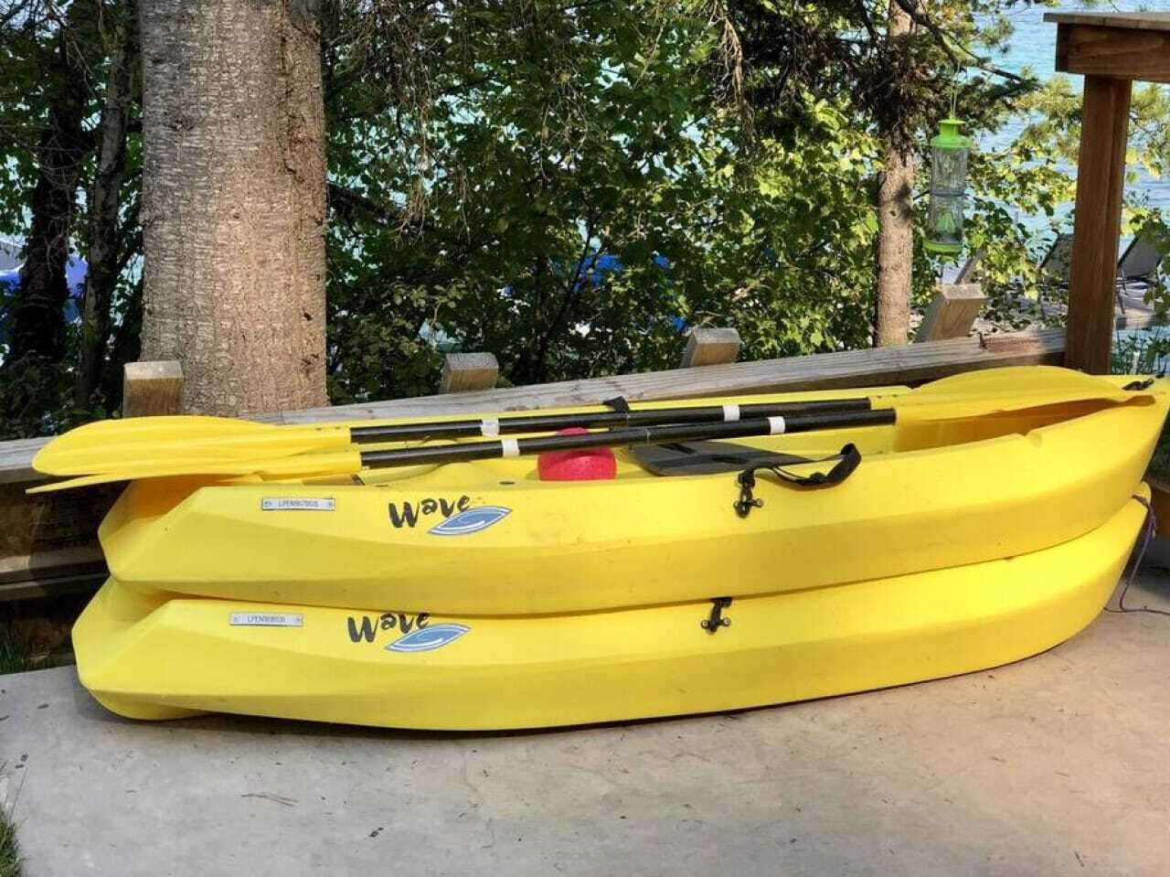 Two yellow kayaks with 'Wave' branding, placed on a concrete surface outdoors.