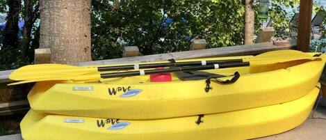 Two yellow kayaks with 'Wave' branding, placed on a concrete surface outdoors.
