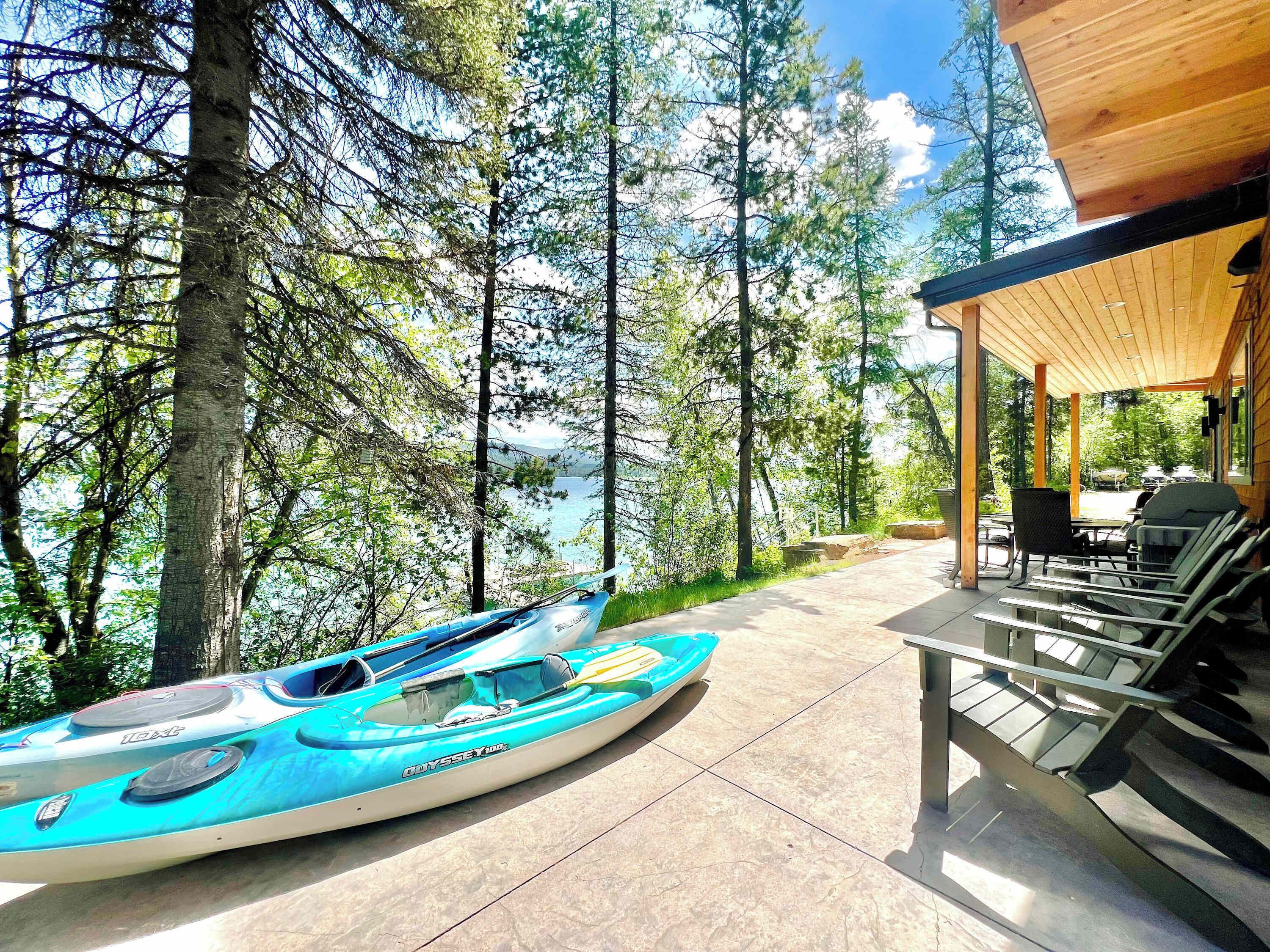 A kayak on a patio with a view of a forest and a lake.