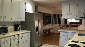Una cocina moderna con armarios blancos, un refrigerador de acero inoxidable, un microondas y una estufa.