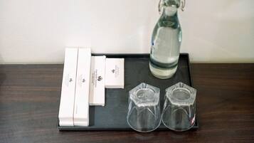 A tray with a water bottle, two glasses, and a set of white cards on a dark wooden surface.