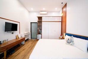 A hotel room with a bed, a desk, a television, a wardrobe, and a small kitchenette. - Co To Center Homestay (Co To)