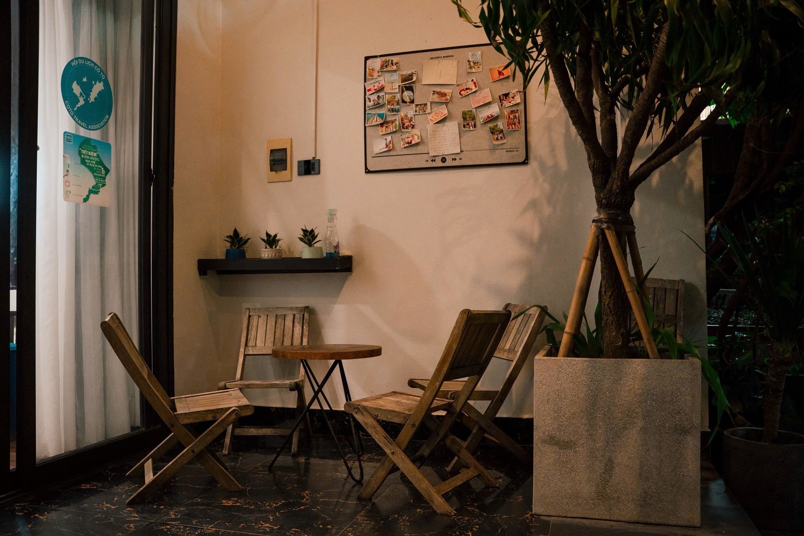 Un coin de pièce avec une chaise en bois, une petite table ronde et une plante en pot.