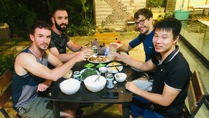 A group of people dining at an outdoor table with various dishes, bowls, and utensils. - Co To Center Homestay (Co To)